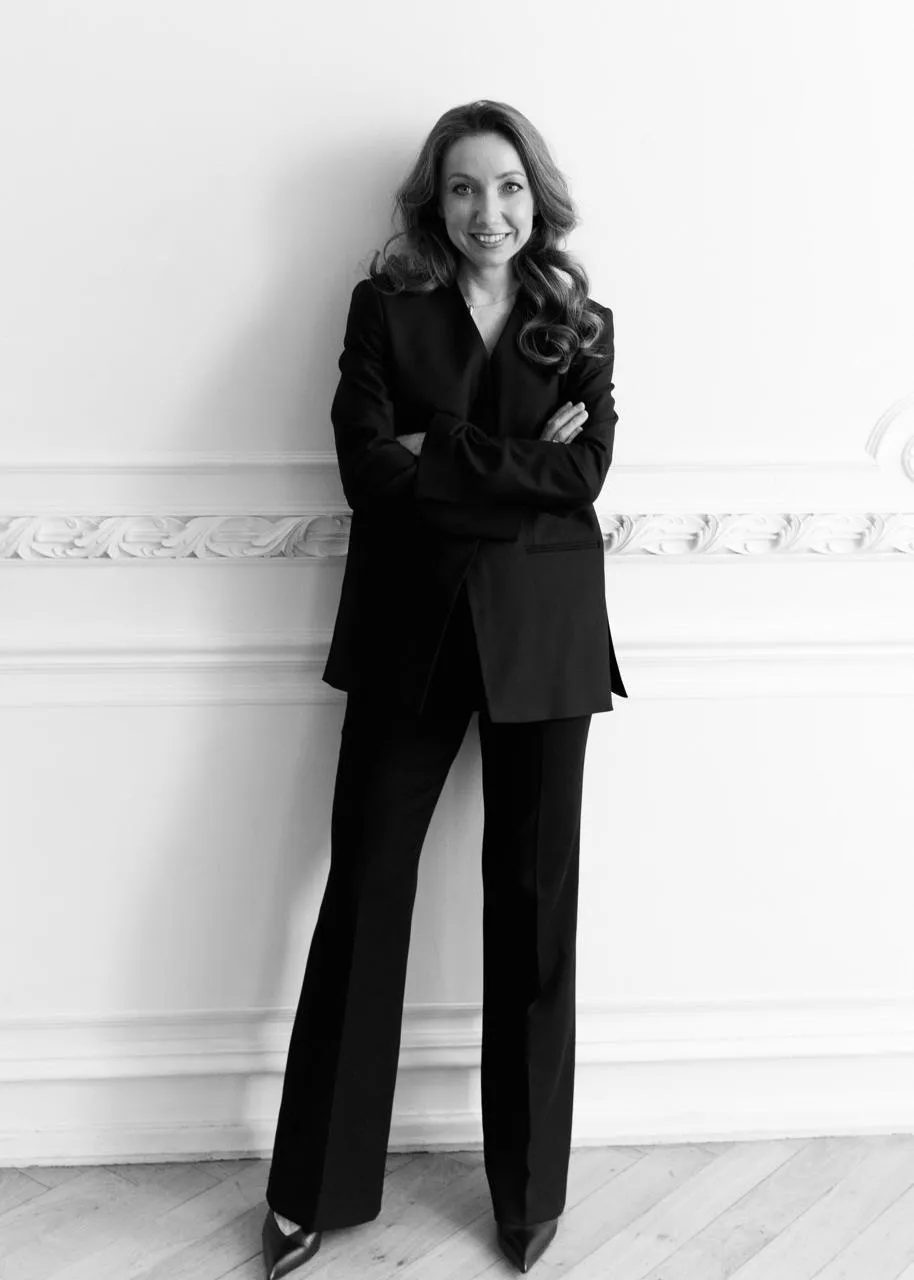 Nadia Nazarova in a black suit against a moulded white wall